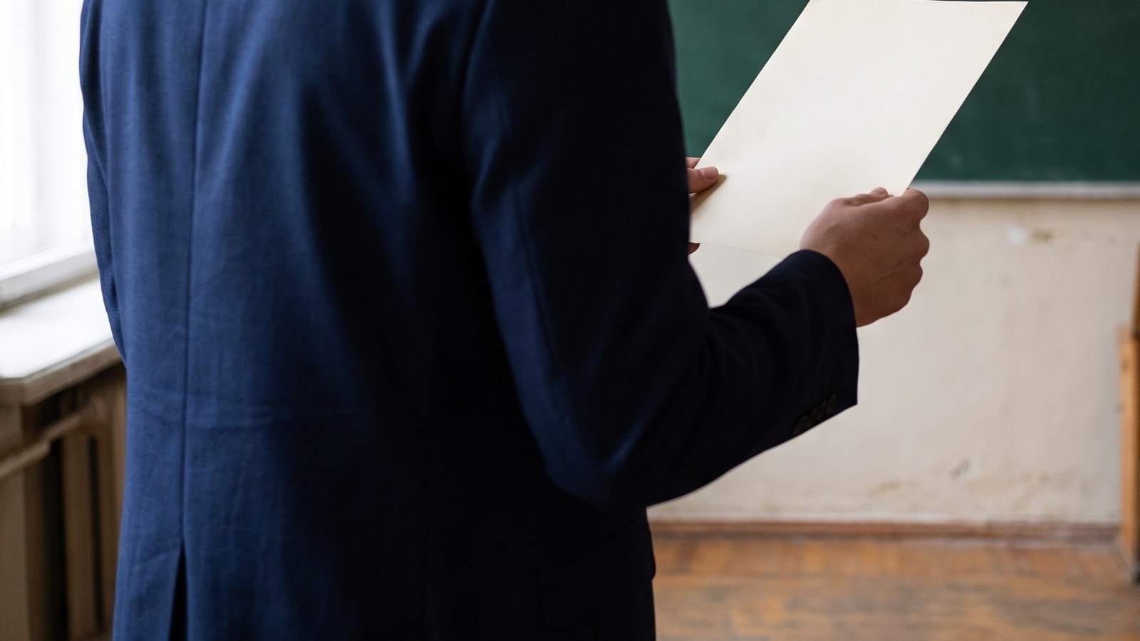 Üniversite seminer odasında bir sayfa tutan ve yüzü görünmeyen akademisyen.